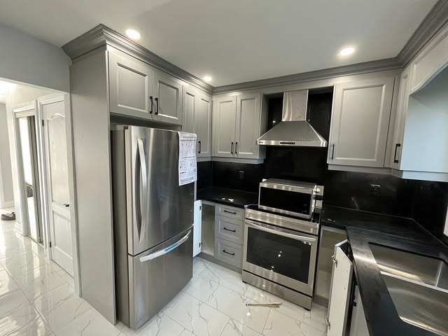 Kitchen renovation with stainless steel appliances and black granite countertops in Brampton