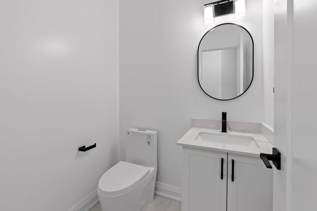 Powder room renovation with round mirror and matte black fixtures in Brampton